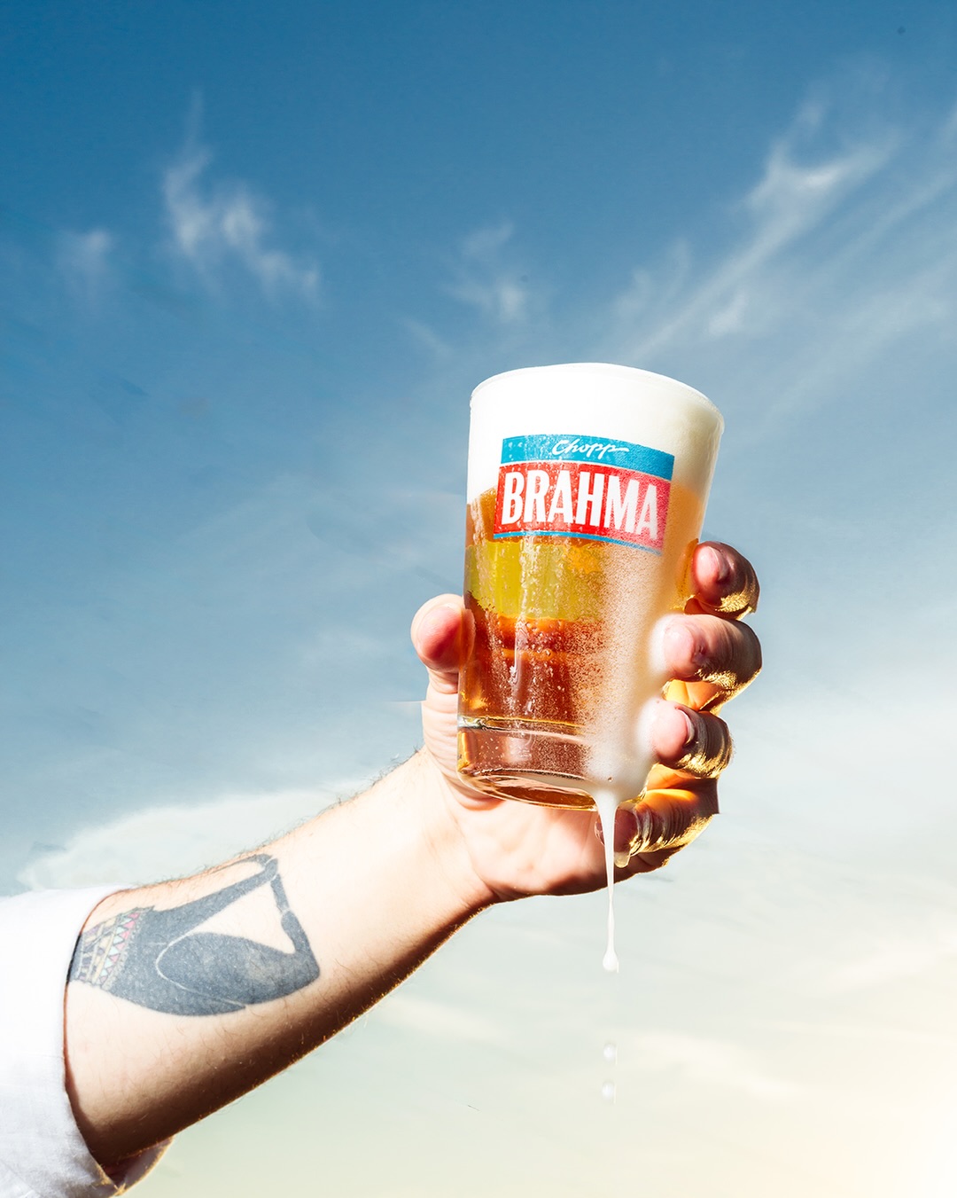 Chopp gelado transbordando contra o céu azul